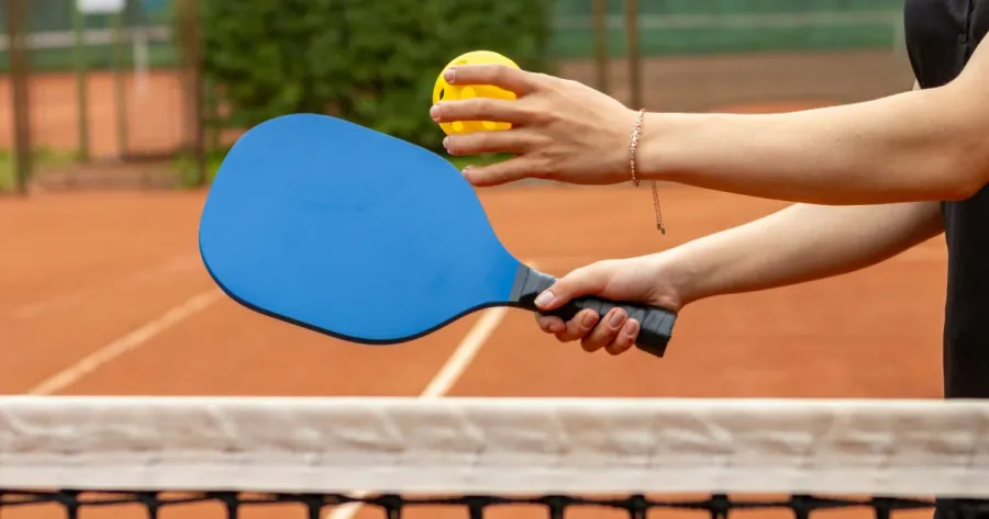 Closeup of a player holding a pickleball paddle.